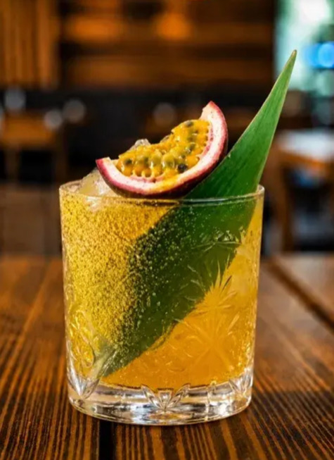 Spiced Passionstar: a golden amber cocktail over ice in a cut-crystal tumbler, garnished with half a passionfruit and a green leaf
